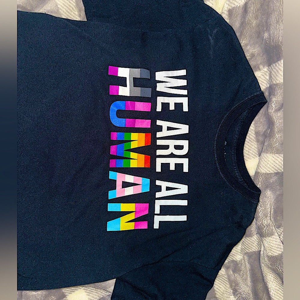 Black unisex t-shirt; “WE ARE ALL HUMAN” LGBTQ representation wording on front